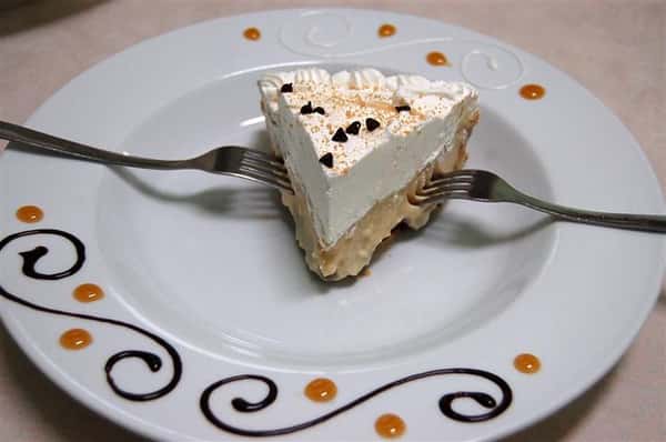 Small slice of pie on a white plate and two forks.