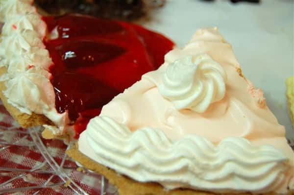 Close up of two different pie slices. One pie is cherry and the other is with a white cream frosting.