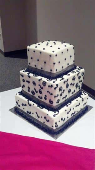Three tier white square cake with navy blue dots and designs.