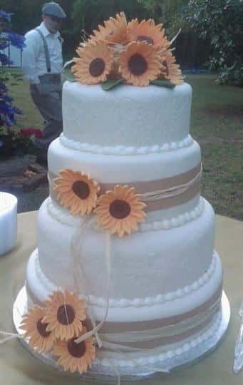 Three tier round white cake with orange sunflowers.