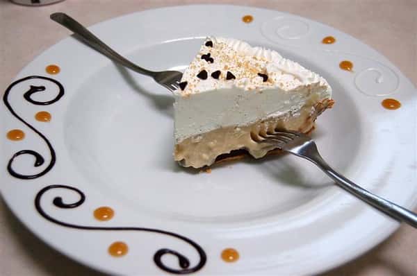 Small slice of pie on a white plate and two forks.