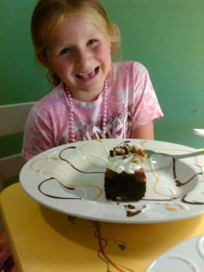 Young girl smiling at the camera with a cake in front of here.