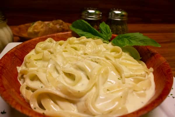 Fettuccini Alfredo in a bowl with basil leaves