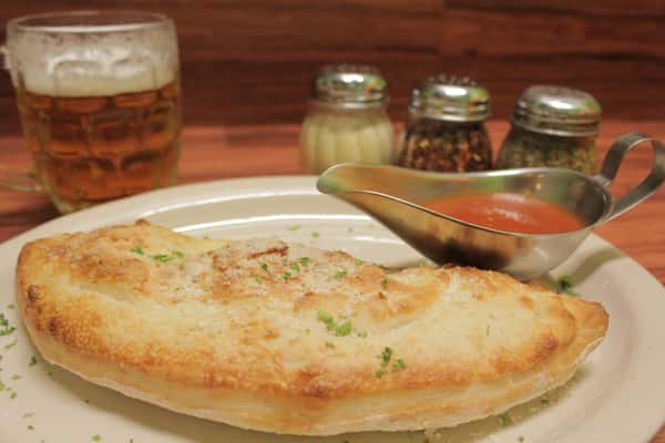 Calzone on a plate with side of marinara sauce