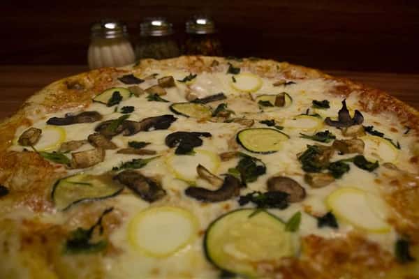Close up View of Giardino Pizza. Pizza topped with tomato sauce, mozzarella, eggplant, spinach, yellow squash, zucchini & mushrooms.