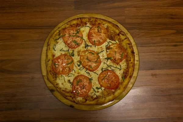 Top view of Caprese Pizza. Pizza topped with tomato sauce, mozzarella, sliced tomato, Italian sausage, black olives, oregano & virgin olive oil.