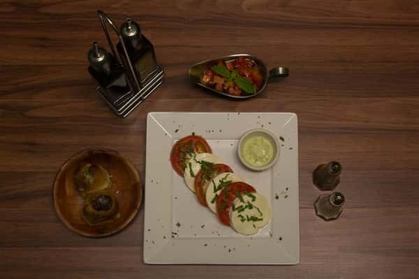 Caprese salad with basil. Garlic knots, olive oil, salt and pepper on the side.