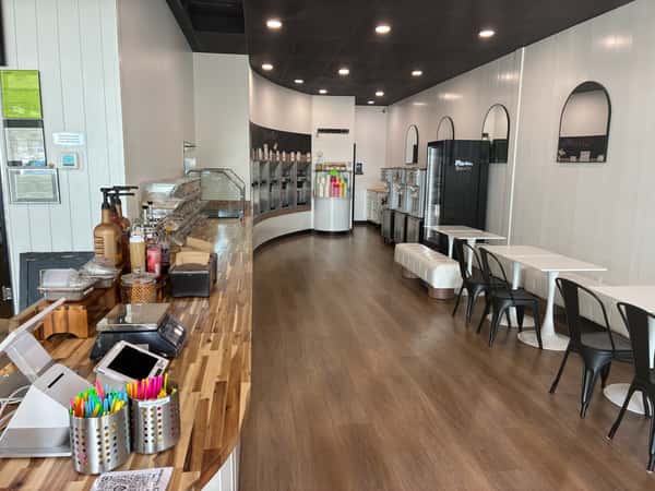 Bright, modern frozen yogurt shop interior with self-serve topping bar, soft serve machines, and cozy seating – clean dessert café layout ideal for family outings and group gatherings.