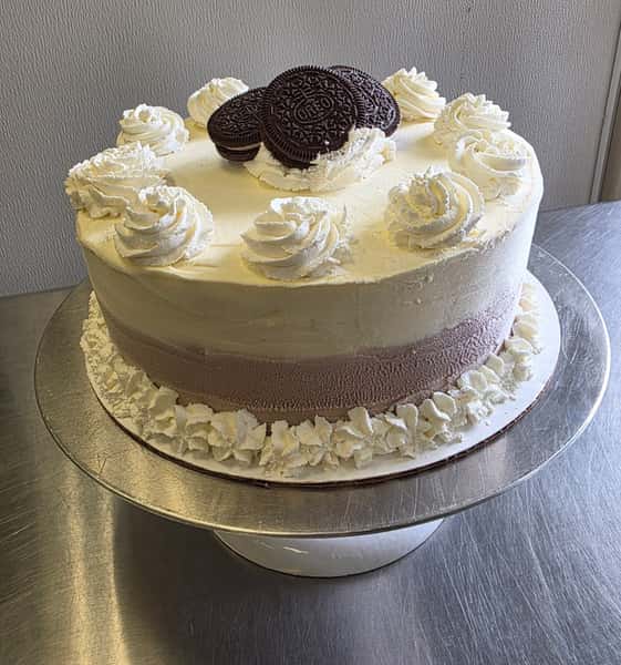 Oreo cookies and cream ice cream cake with whipped frosting rosettes – layered celebration cake topped with chocolate sandwich cookies, ideal for birthdays and special events.