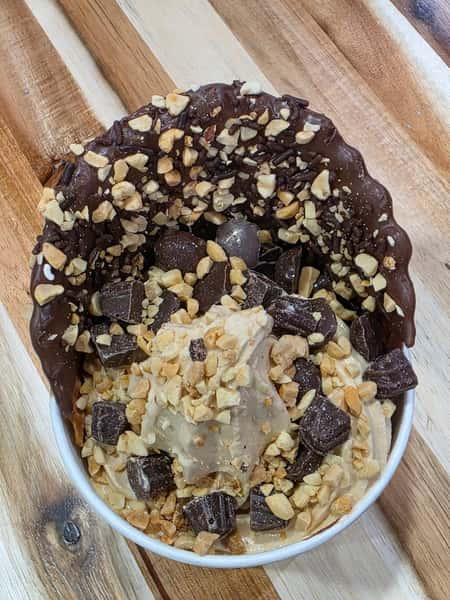 Peanut butter frozen yogurt topped with chocolate chunks and chopped nuts in a chocolate-coated waffle bowl – gourmet froyo creation for a dessert bar menu.