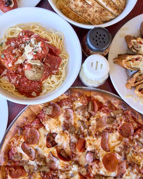 Pizza and pasta dishes spread on table