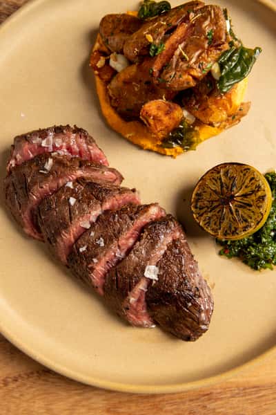 sliced grilled steak with mashed sweet potatoes and grilled lemon