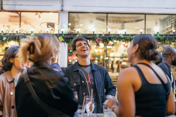 man laughing outside with cocktails