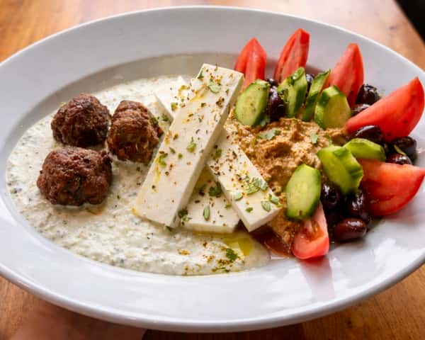 Mediterranean plate with falafel, feta cheese, pita bread, and fresh cucumber tomato salad