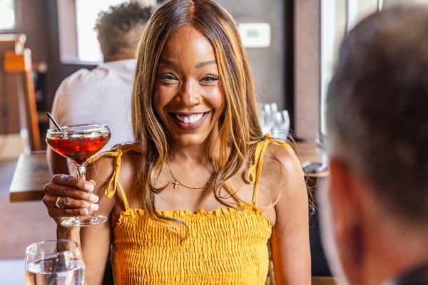 Woman enjoying a craft cocktail while dining with a companion at the restaurant.