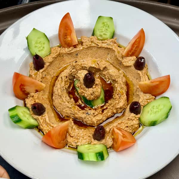 Creamy hummus dip garnished with olives and fresh vegetables for dipping