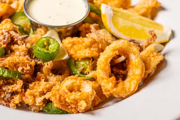 Crispy fried calamari with green peppers, lemon wedges, and creamy dipping sauce.
