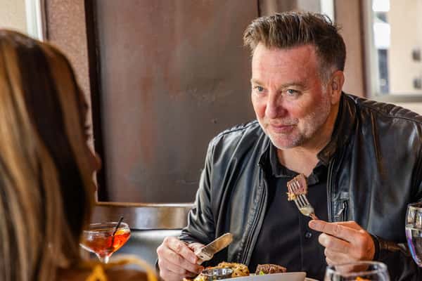 Man enjoying a steak dinner while dining with a woman at a casual upscale restaurant.