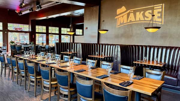 Elegant restaurant dining room with neatly set tables, comfortable seating, and warm contemporary décor