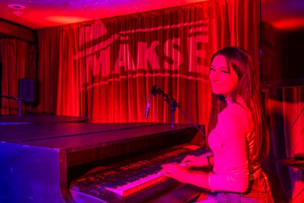 Pianist performing on the Makse live music stage under vibrant red lighting.