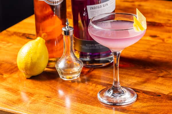 Pink gin cocktail served in a coupe glass with a lemon twist at the restaurant bar.