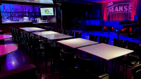 Private dining and event space with banquet tables, stage lighting, and modern restaurant lounge atmosphere