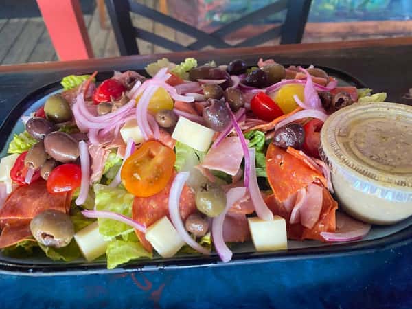 Italian chopped salad with romaine lettuce, olives, cherry tomatoes, red onions, salami, cheese cubes, and vinaigrette dressing.