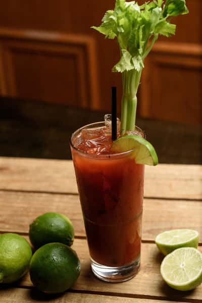 Bloody mary in glass with lime, celary, and black straw