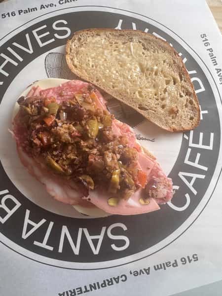 Open sandwich with cured meats and olive salad on Santa Barbara Hives placemat