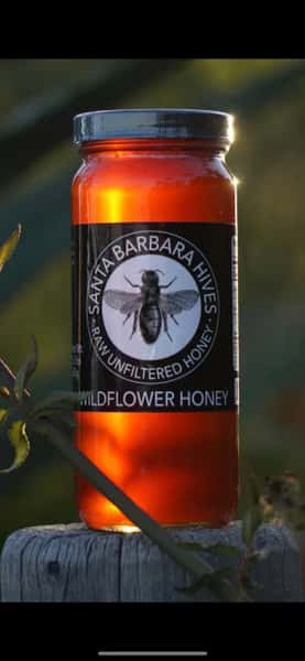 Glass jar of Santa Barbara Hives raw wildflower honey glowing in sunset light