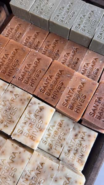 Rows of handmade soap bars engraved with 'Santa Barbara Hives'.