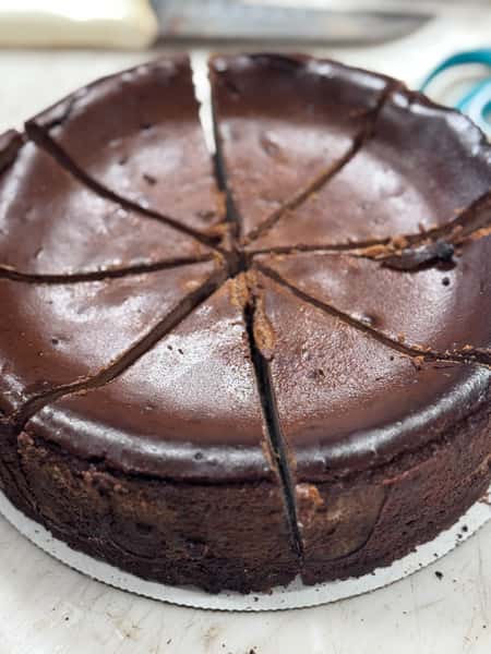 Chocolate cheesecake sliced into 8 pieces on a white base