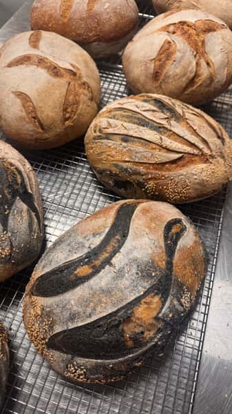 Loaves of artisan bread with decorative scoring on a cooling rack