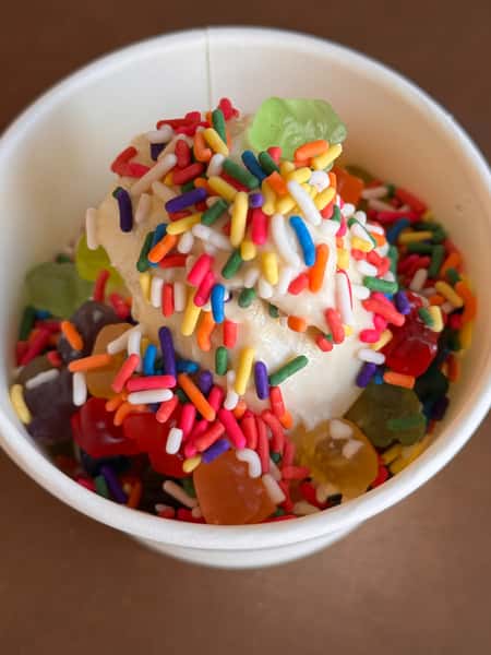 Vanilla ice cream topped with gummy bears and rainbow sprinkles.