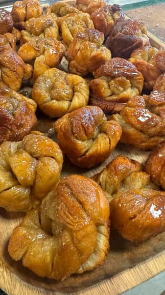 Golden brown glazed sticky buns on a wooden tray.