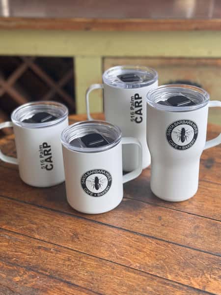 Set of white mugs and tumblers branded with "Santa Barbara Hives Café + Bakery"