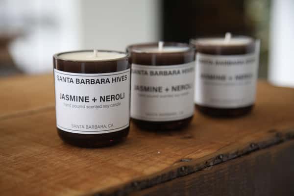Three brown "Jasmine + Neroli" scented candles from Santa Barbara Hives on wooden surface