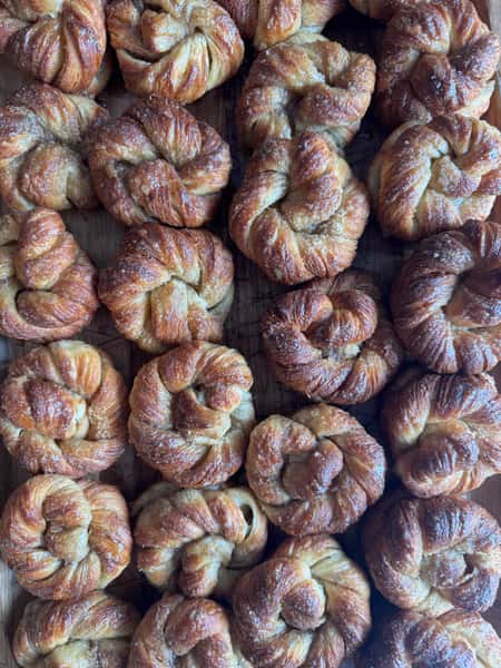 Batch of golden-brown twisted pastries arranged on a wooden surface