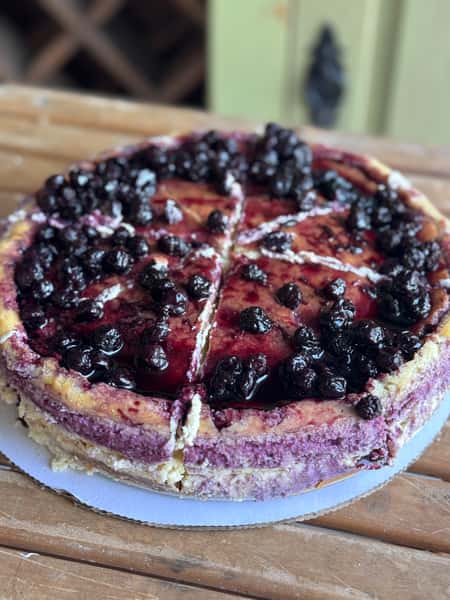 A rich cheesecake topped with blueberry compote, cut into individual slices.