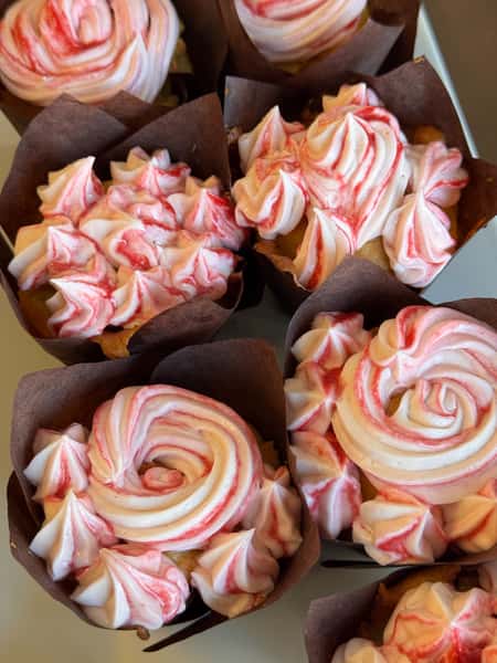 Cupcakes with swirled pink and white frosting in brown wrappers
