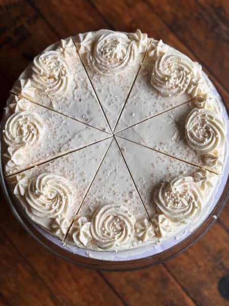 White frosted cake with pearl decorations and piped swirls