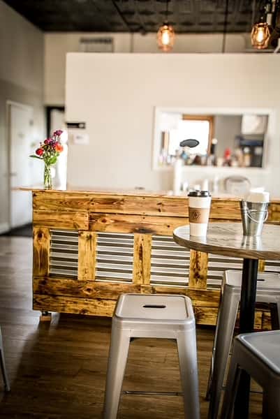 Rustic wooden counter and metal stools in the warm interior of AJ's Riverside.