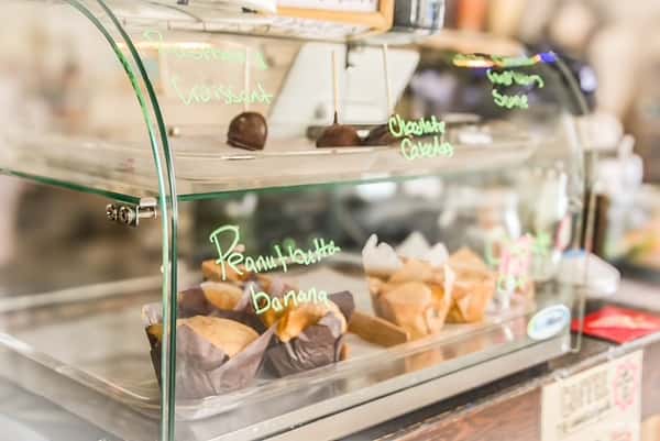 Glass display case filled with muffins and chocolate desserts at AJ's Riverside.