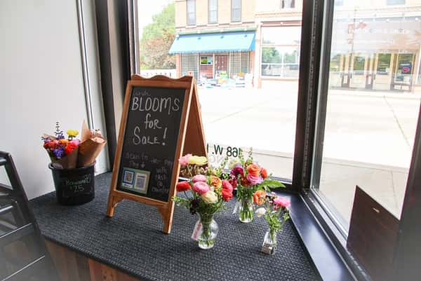Colorful flower bouquets and "Blooms for Sale" sign in the window at AJ's Riverside.