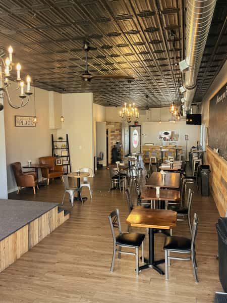 AJ's Riverside restaurant interior with dining tables, stage area, wood floors, and decorative tin ceiling.