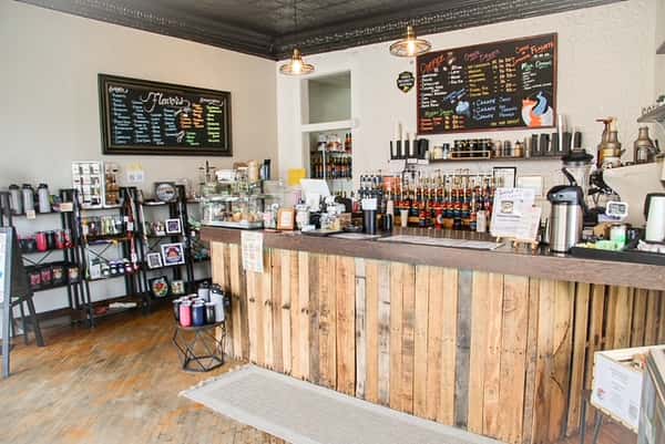 AJ's Riverside coffee shop interior featuring a rustic wood counter, black menus, and retail shelves.