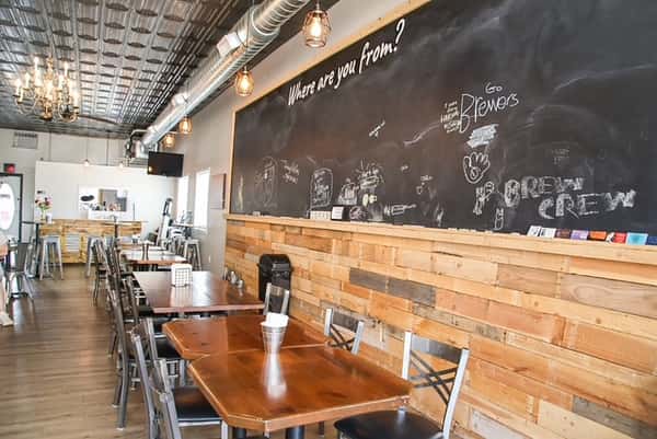 Interior dining area at AJ's Riverside featuring a large chalkboard wall, wood paneling, and tables.