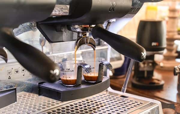 Espresso pouring into two glass cups from a coffee machine at AJ's Riverside.