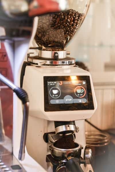 White coffee grinder with beans filling portafilter at AJ's Riverside.