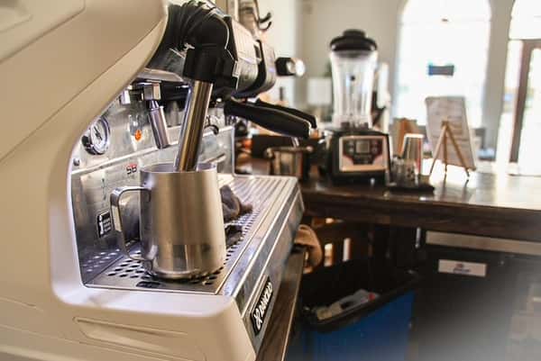 White and silver espresso machine and milk pitcher on the counter at AJ's Riverside restaurant.